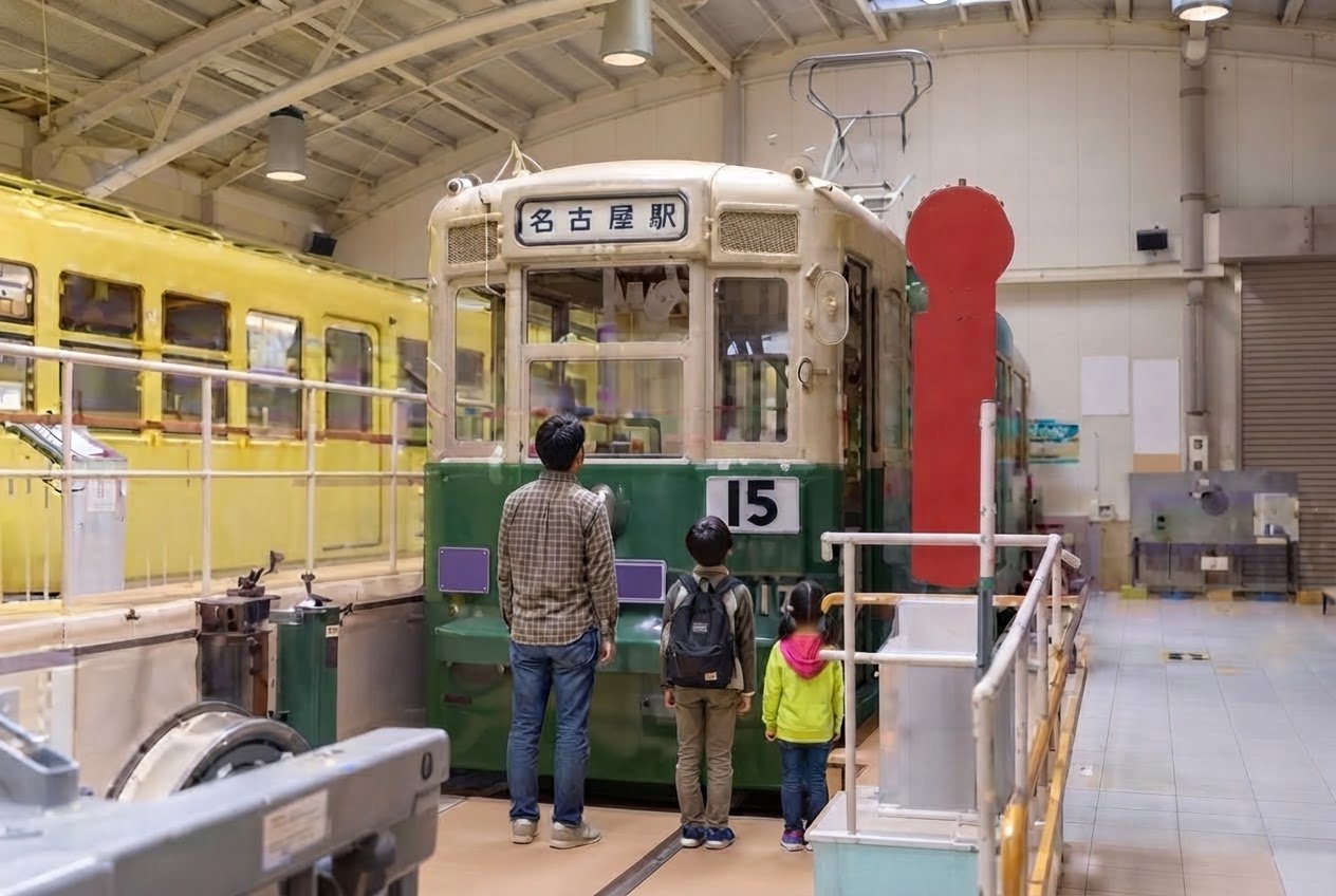 レトロでんしゃ館に展示された緑とクリーム色の市電を見上げる父親と子ども2人の後ろ姿